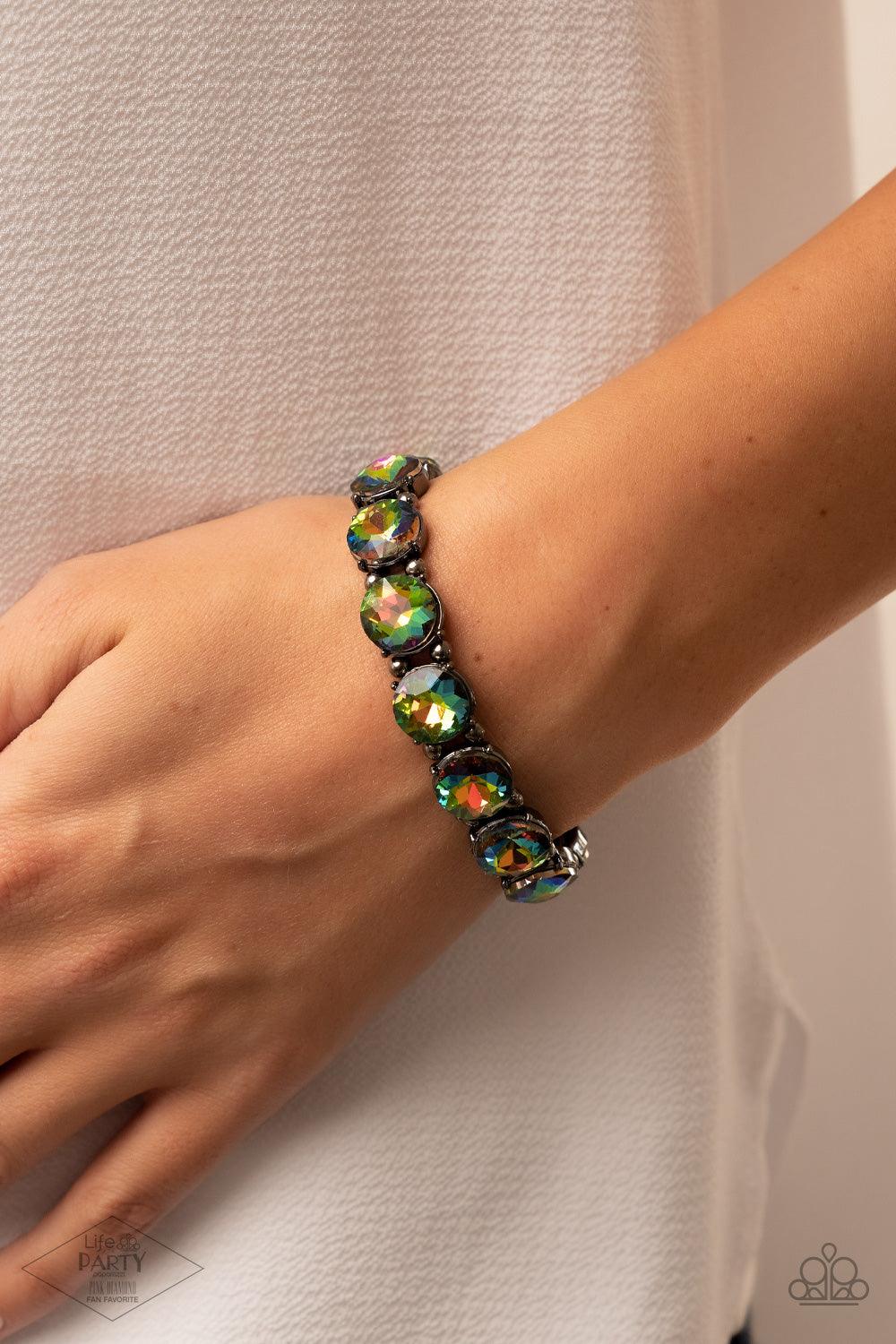 Paparazzi Accessories Glitzy Glamorous - Multi A row of exaggerated oil spill rhinestones is threaded along stretchy bands and wraps boldly around the wrist. Dainty gunmetal beads separate each rhinestone, adding a metallic grit to the piece. Sold as one