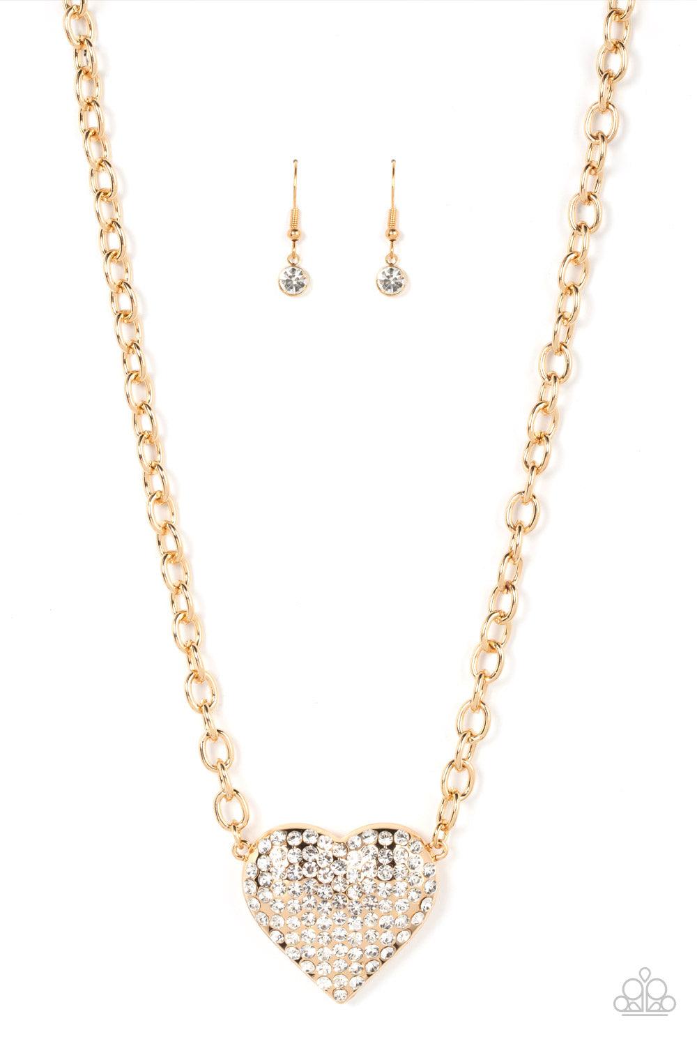Paparazzi Accessories Heartbreakingly Blingy - Gold A dramatically oversized gold heart frame is encrusted in row after row of dazzling white rhinestones, resulting in a heart-racing sparkle below the collar. Features an adjustable clasp closure. Sold as