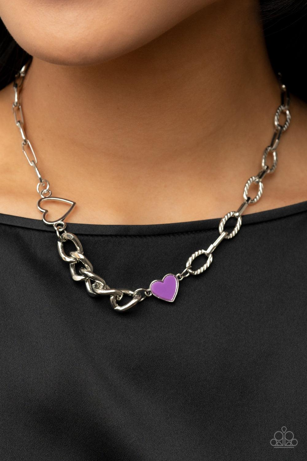 Paparazzi Accessories Little Charmer - Purple A pair of shiny silver and purple hearts asymmetrically adorn sections of mismatched silver chain, resulting in a flirtatious pop of color below the collar. Features an adjustable clasp closure. Sold as one in