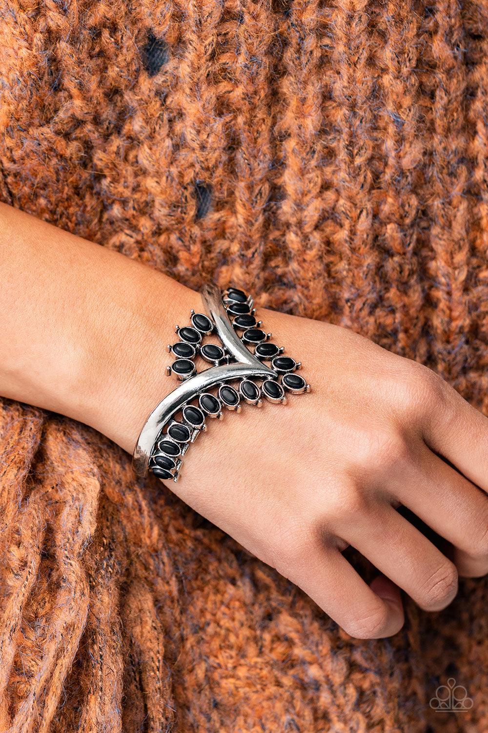 Paparazzi Accessories Teton Tiara - Black Black oval stones, encased in studded silver frames, line the edge of a daring V-shaped silver cuff. A gathering of black stones adorns the center of the bracelet, adding a finishing touch to the rustically regal