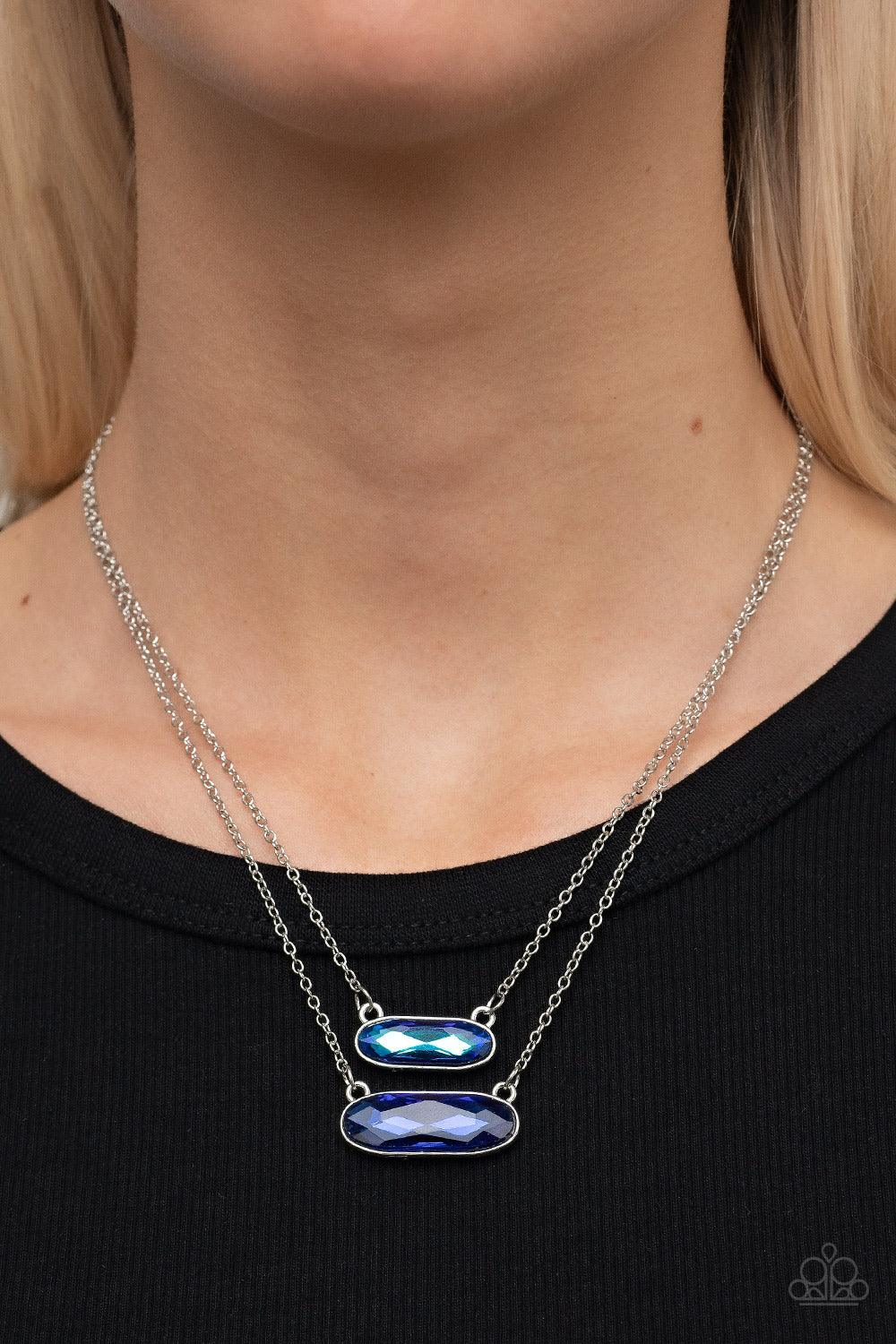 Paparazzi Accessories Double Bubble Burst - Blue Featuring faceted oblong cuts, a UV blue gem is delicately suspended above a slightly larger glittery blue gem below the collar for a stellar double-stacked display. Features an adjustable clasp closure. So