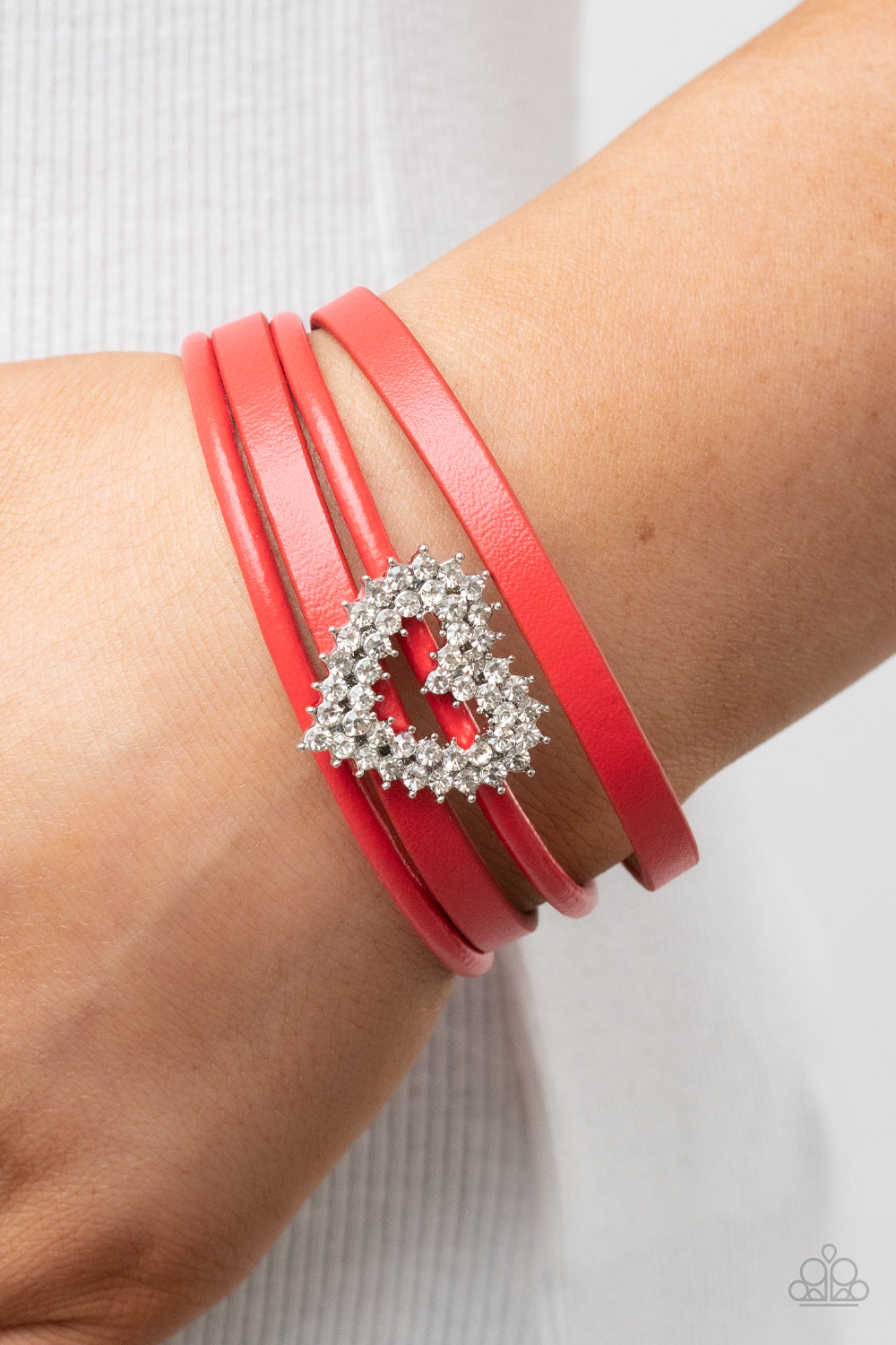 Paparazzi Accessories Wildly in Love - Red Featuring pronged silver fittings, two rows of glassy white rhinestones stack into a sparkly heart frame that is threaded along layers of red leather strands around the wrist. Features a magnetic closure. Sold as