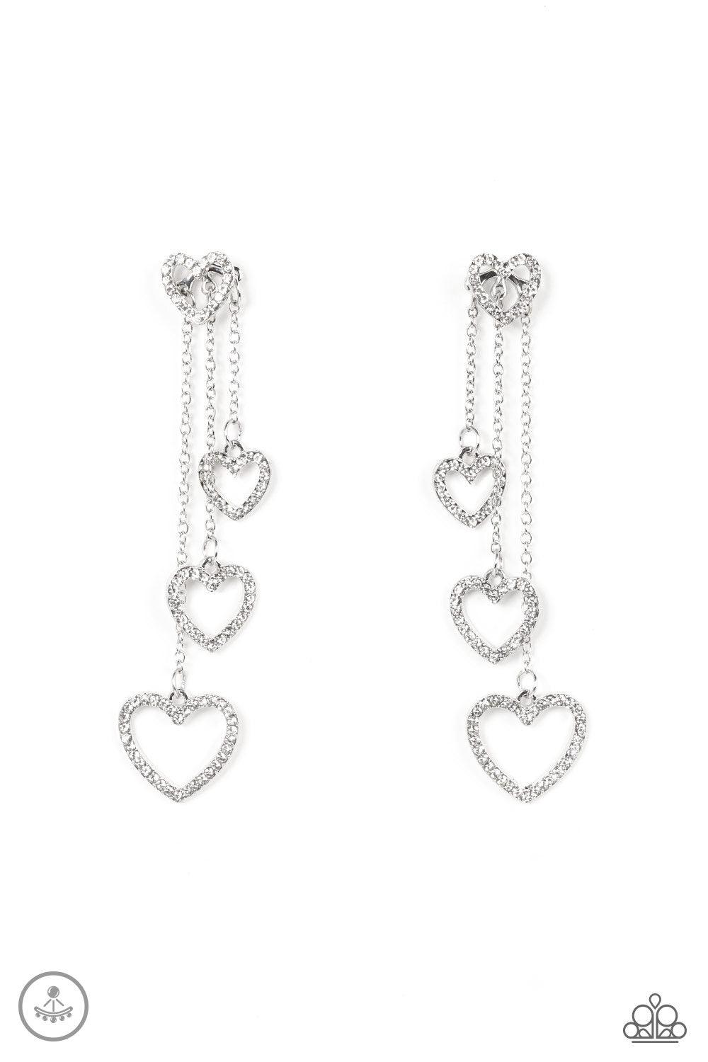 Paparazzi Accessories Falling In Love - White Encrusted in dainty white rhinestones, a glittery silver heart fitting attaches to a double-sided post designed to fasten behind the ear. Attached to dainty silver chains of varying lengths, a glittery collect