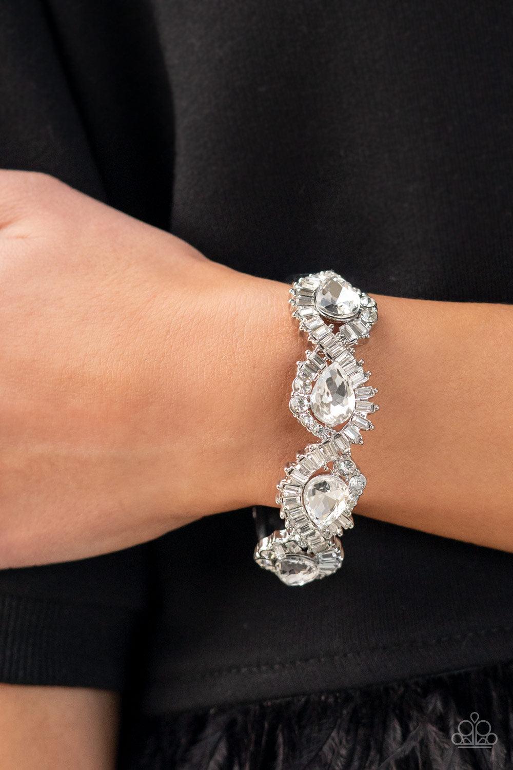 Paparazzi Accessories For the Win - White Ribbons of emerald and round cut rhinestones loop around dramatically oversized teardrop rhinestones, resulting in an explosion of sparkle across the front of a jaw-dropping bangle-like bracelet. Features a hinged