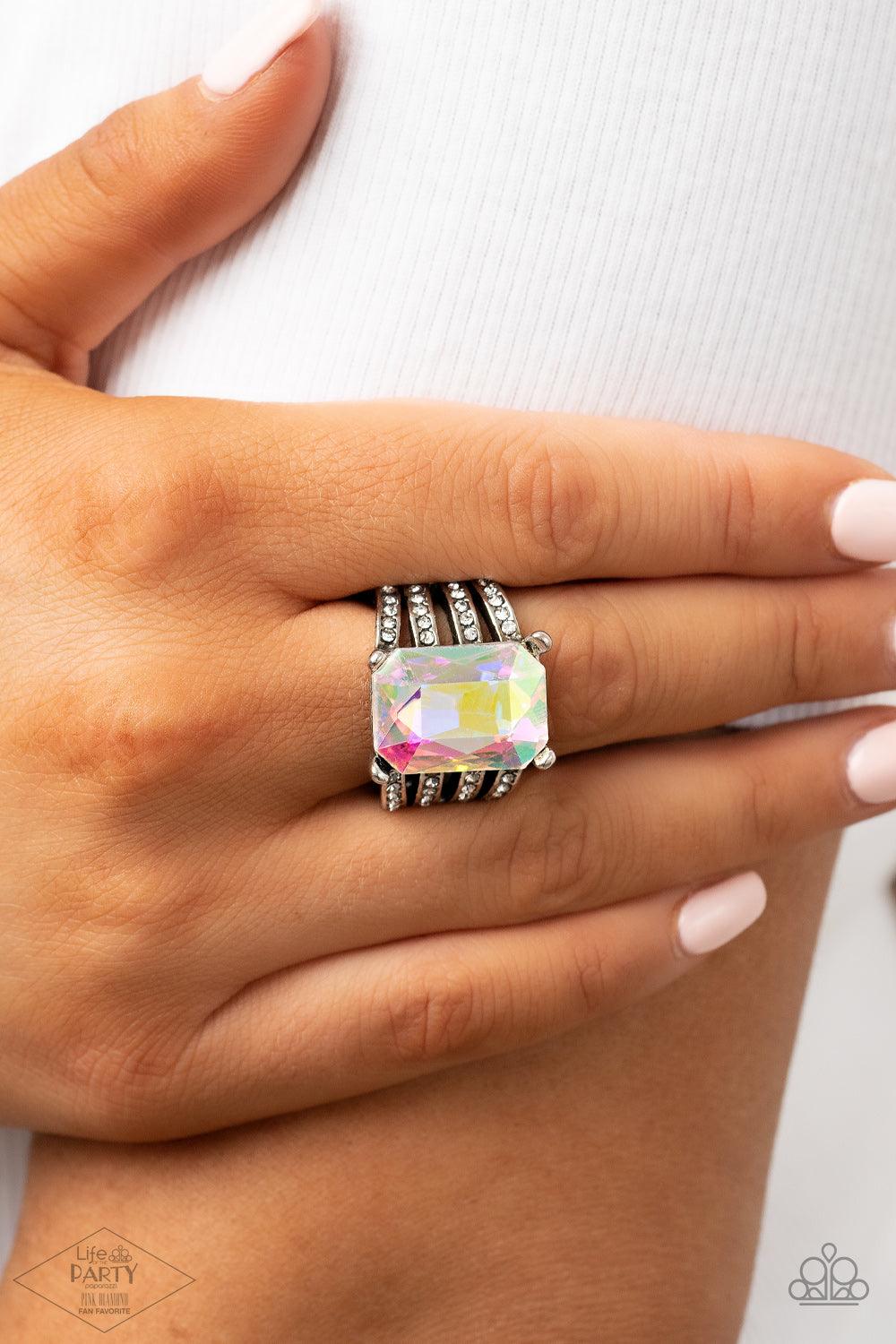 Paparazzi Accessories Expect Heavy REIGN - Multi Featuring a regal emerald style cut, an oversized iridescent gem is pressed into the center of stacked silver bands radiating with dainty white rhinestones for a dramatic look. Features a stretchy band for