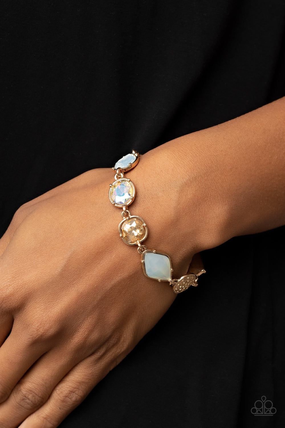 Paparazzi Accessories Jewelry Box Bauble - Gold Encased in pronged gold fittings, a mismatched collection of golden, iridescent, and opal rhinestones delicately links with a studded gold frame around the wrist for a sentimental sparkle. Features an adjust