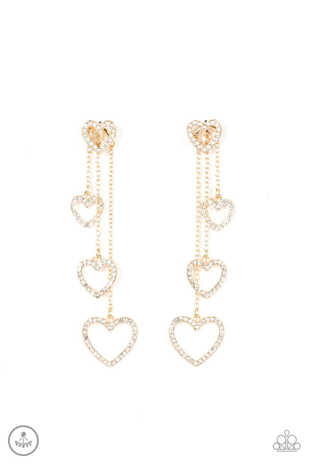 Paparazzi Accessories Falling In Love - Gold Encrusted in dainty white rhinestones, a glittery gold heart fitting attaches to a double-sided post designed to fasten behind the ear. Attached to dainty gold chains of varying lengths, a glittery collection o