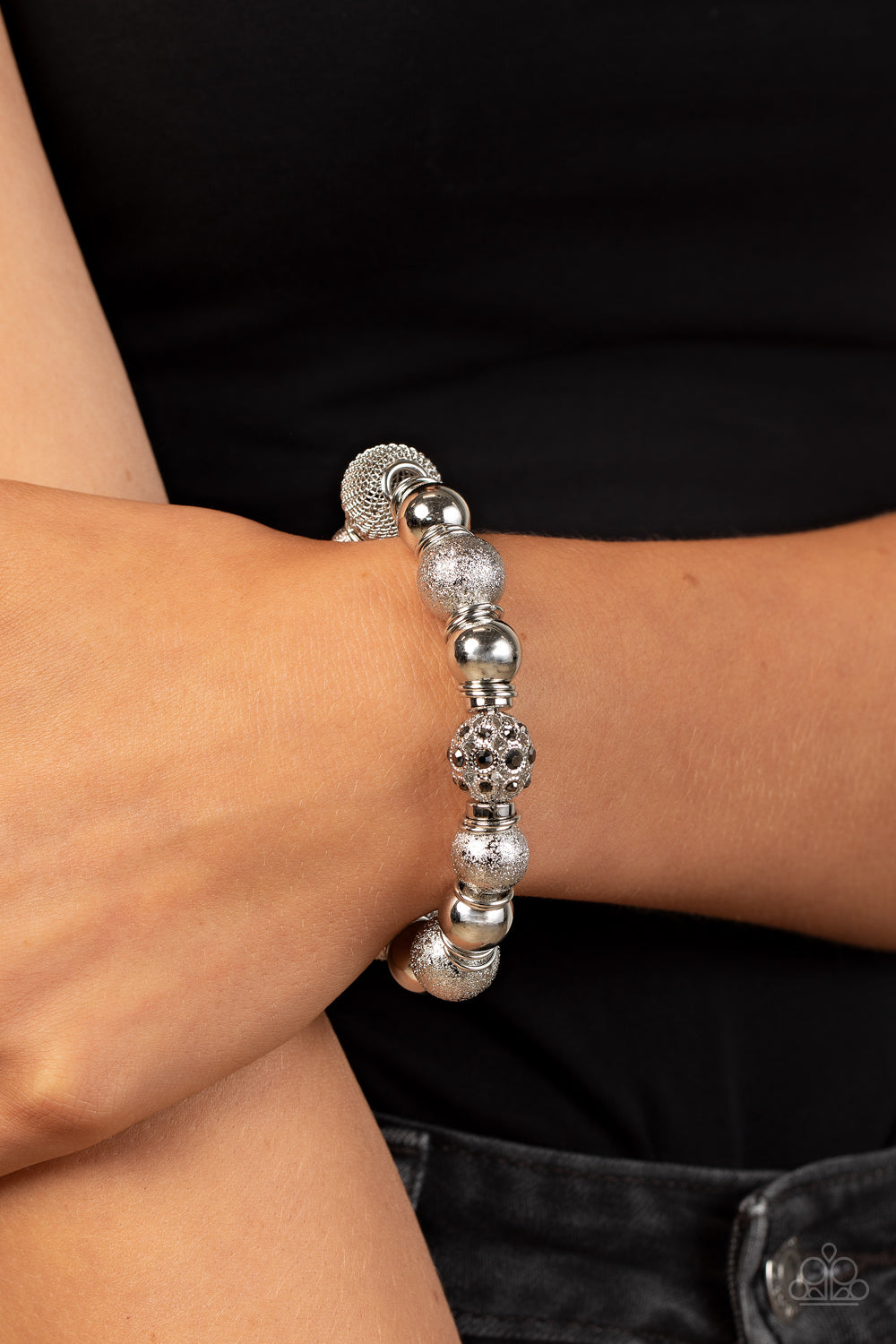 Paparazzi Accessories We Totally Mesh - Silver An oversized collection of shimmery silver beads, silver rings, hematite rhinestone dotted accents, and wire mesh beads are threaded along stretchy bands around the wrist for a glitzy finish. Featured inside