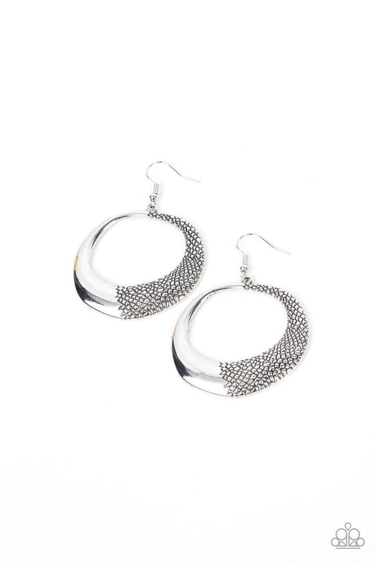 Paparazzi Accessories Downtown Jungle - Silver One side of an asymmetrical silver hoop is embossed in rugged pebble like texture, culminating in a wildly abstract frame. Earring attaches to a standard fishhook fitting. Sold as one pair of earrings. Jewelr
