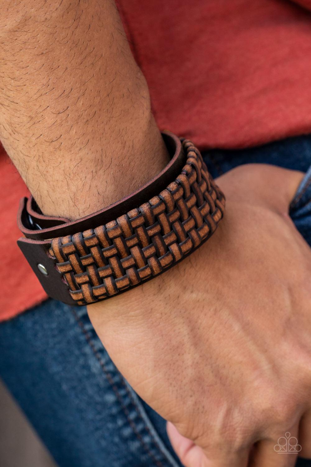 Paparazzi Accessories Urban Expansion - Brown Distressed leather laces weave into a wicker-like pattern, creating a thick band of texture that wraps around a leather band. The textured overlay is studded in place across the front of the brown leather band