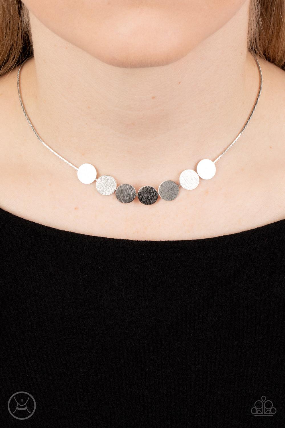 Paparazzi Accessories Slimmer Glimmer - Silver Featuring shimmery scratched surfaces, a glimmering collection of dainty silver discs are fitted in place along a silver snake chain around the neck for a sleek finish. Features an adjustable clasp closure. S