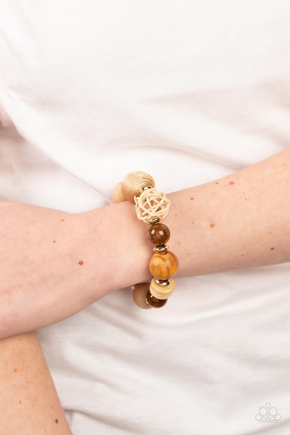 Paparazzi Accessories Happily Homespun - Brown Infused with a single rattan sphere, a mismatched collection of oversized wooden beads, tan thread wrapped beads, dainty gold accents, and glassy brown beads are threaded along stretchy bands around the wrist