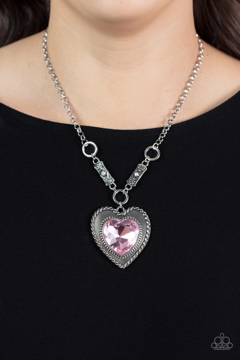 Paparazzi Accessories Heart Full of Fabulous - Pink Bordered in spun silver ribbons, an oversized Gossamer Pink heart gem is pressed into a silver heart frame below the collar. The flirtatious pendant attaches to silver rings and decorative silver frames