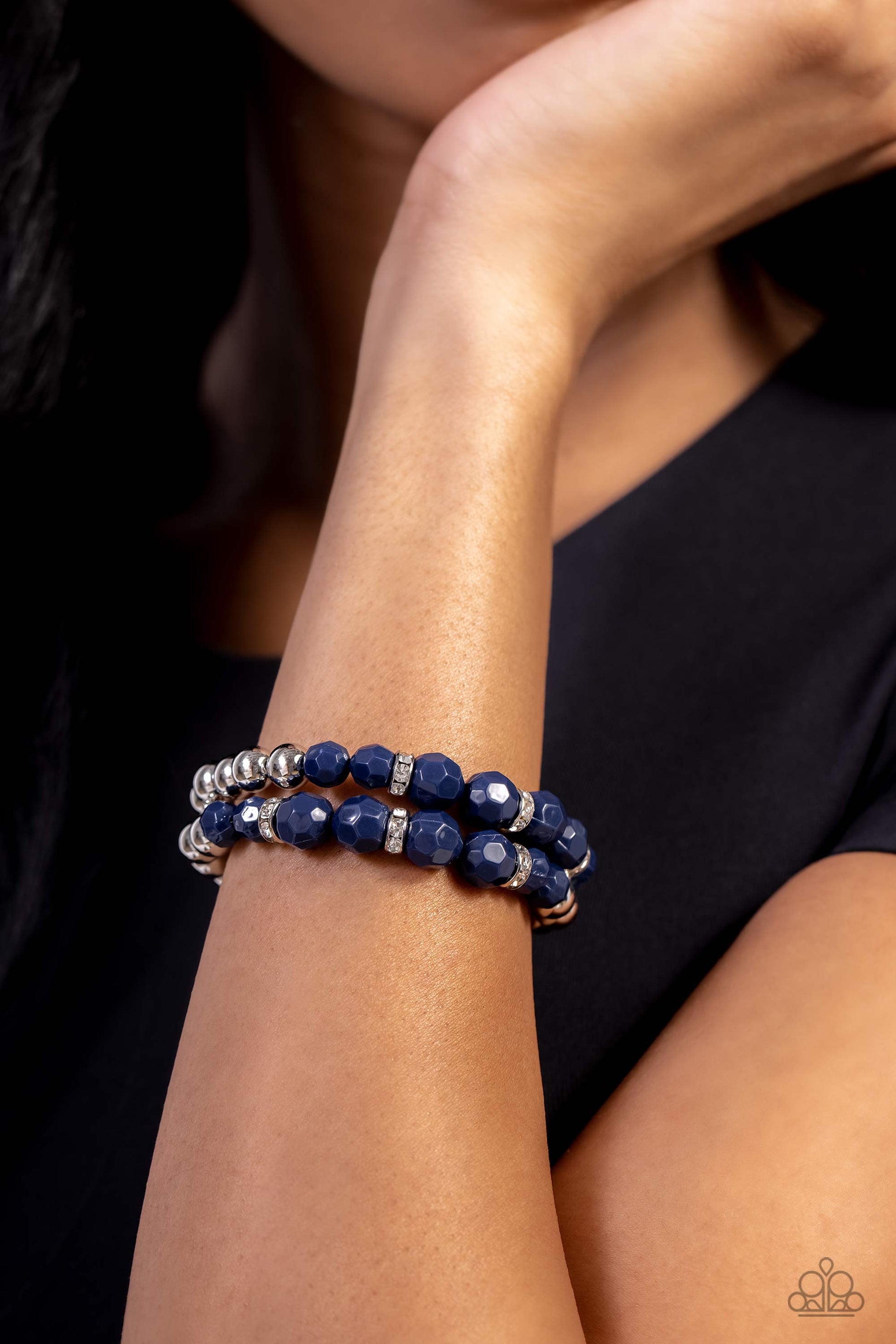 Paparazzi Accessories Two by Two Twinkle - Blue Infused with shiny silver beads, white rhinestone encrusted silver rings and faceted navy blue beads are threaded along a pair of stretchy bands around the wrist for a polished pop of color. Sold as one pair