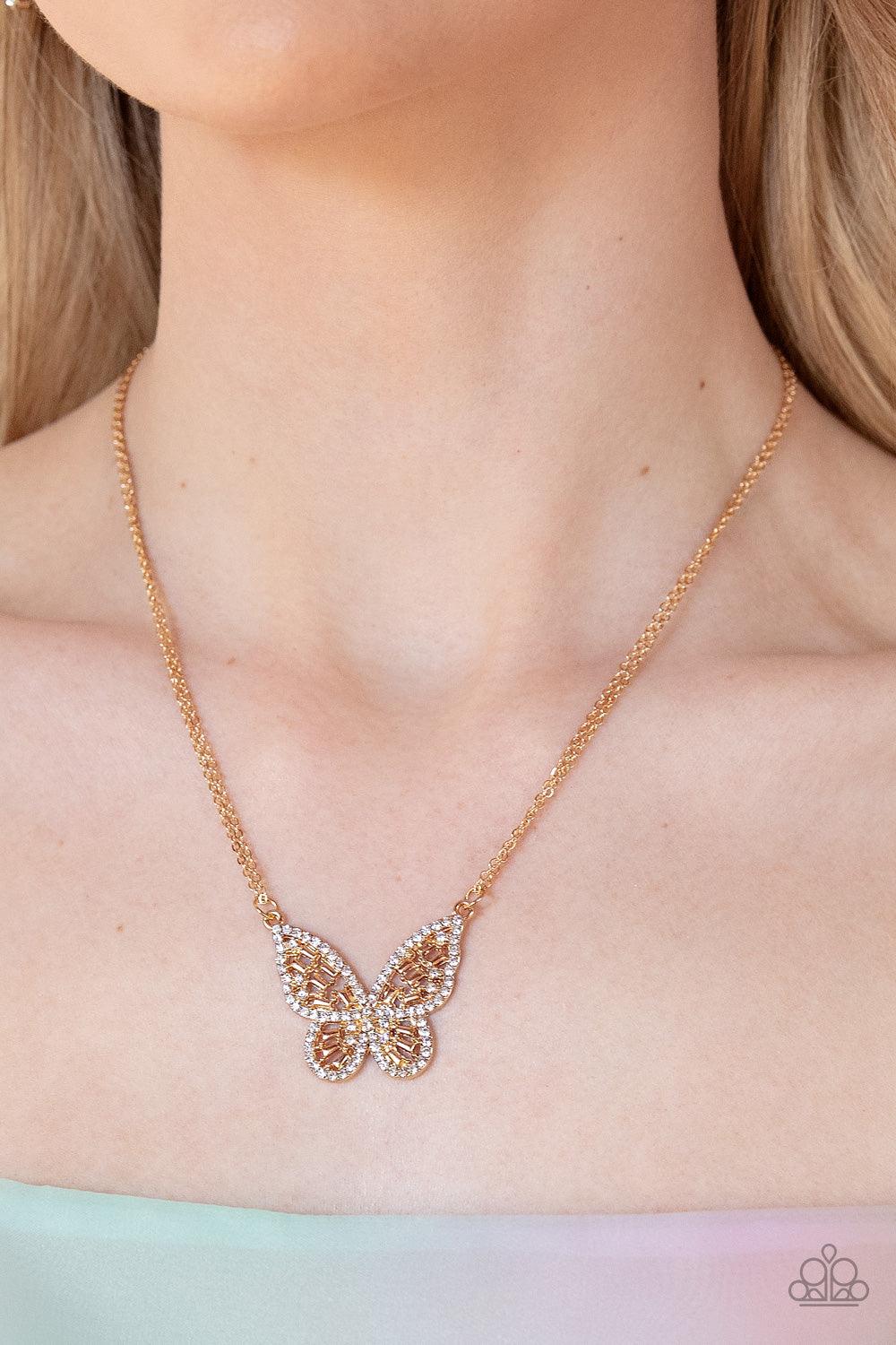 Paparazzi Accessories Baroque Butterfly - Gold Bordered in glassy white rhinestones, an airy gold butterfly is dotted in dainty white rhinestones and shiny gold emerald-like accents as it flutters from two chains below the collar for an enchanting fashion