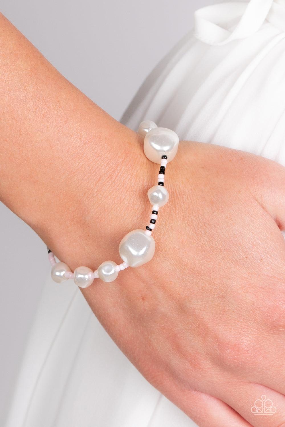 Paparazzi Accessories Contemporary Coastline - Pink Irregular-shaped pearls in varying sizes are scattered amongst Gossamer Pink, black, and silvery seed beads that are threaded along a wire, resulting in a refreshing and playful style around the wrist. F