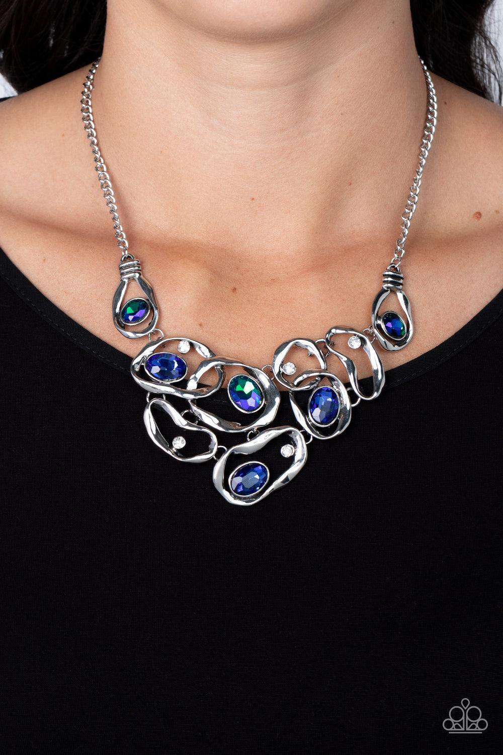 Paparazzi Accessories Warp Speed - Blue Warped silver frames asymmetrically curl around dainty white rhinestones and blue and iridescent gem accents, interlocking into a contemporary statement piece below the collar. Features an adjustable clasp closure.