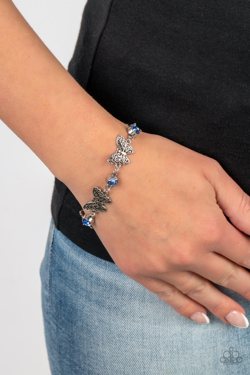 Paparazzi Accessories Has a WING to It - Blue Featuring filigree filled wings, dainty silver butterflies alternate with blue rhinestones around the wrist for a whimsical sparkle. Features an adjustable clasp closure. Sold as one individual bracelet. Jewel