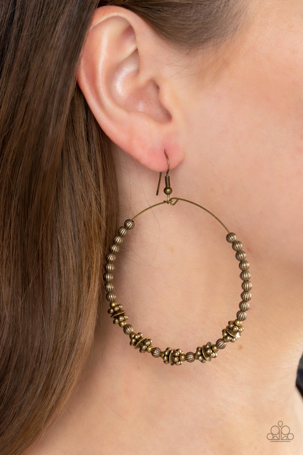 Paparazzi Accessories Simple Synchrony - Brass A dainty collection of ornate brass beads, studded brass rings, and brass discs are threaded along a dainty brass wire, resulting in a rustic hoop. Earring attaches to a standard fishhook fitting. Sold as one