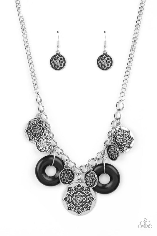 Paparazzi Accessories Western Zen - Black A collection of silver discs, embellished with intricate mandala-like designs, dances along a thick silver chain, with a pair of polished black stone rings adding a pop of color to the rustic design. Features an a