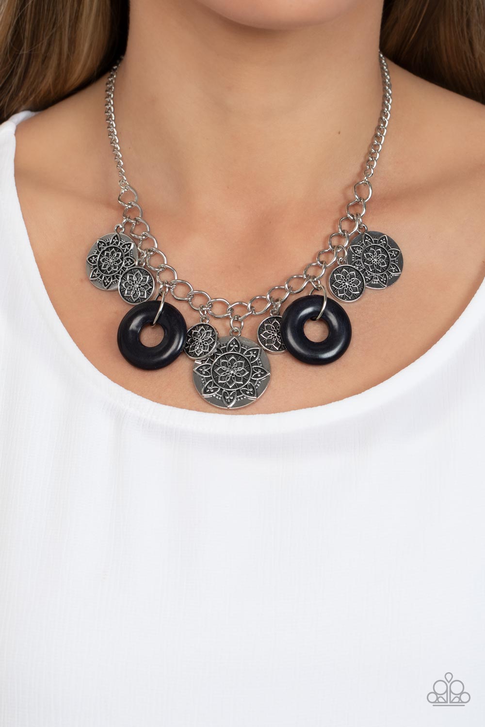Paparazzi Accessories Western Zen - Black A collection of silver discs, embellished with intricate mandala-like designs, dances along a thick silver chain, with a pair of polished black stone rings adding a pop of color to the rustic design. Features an a