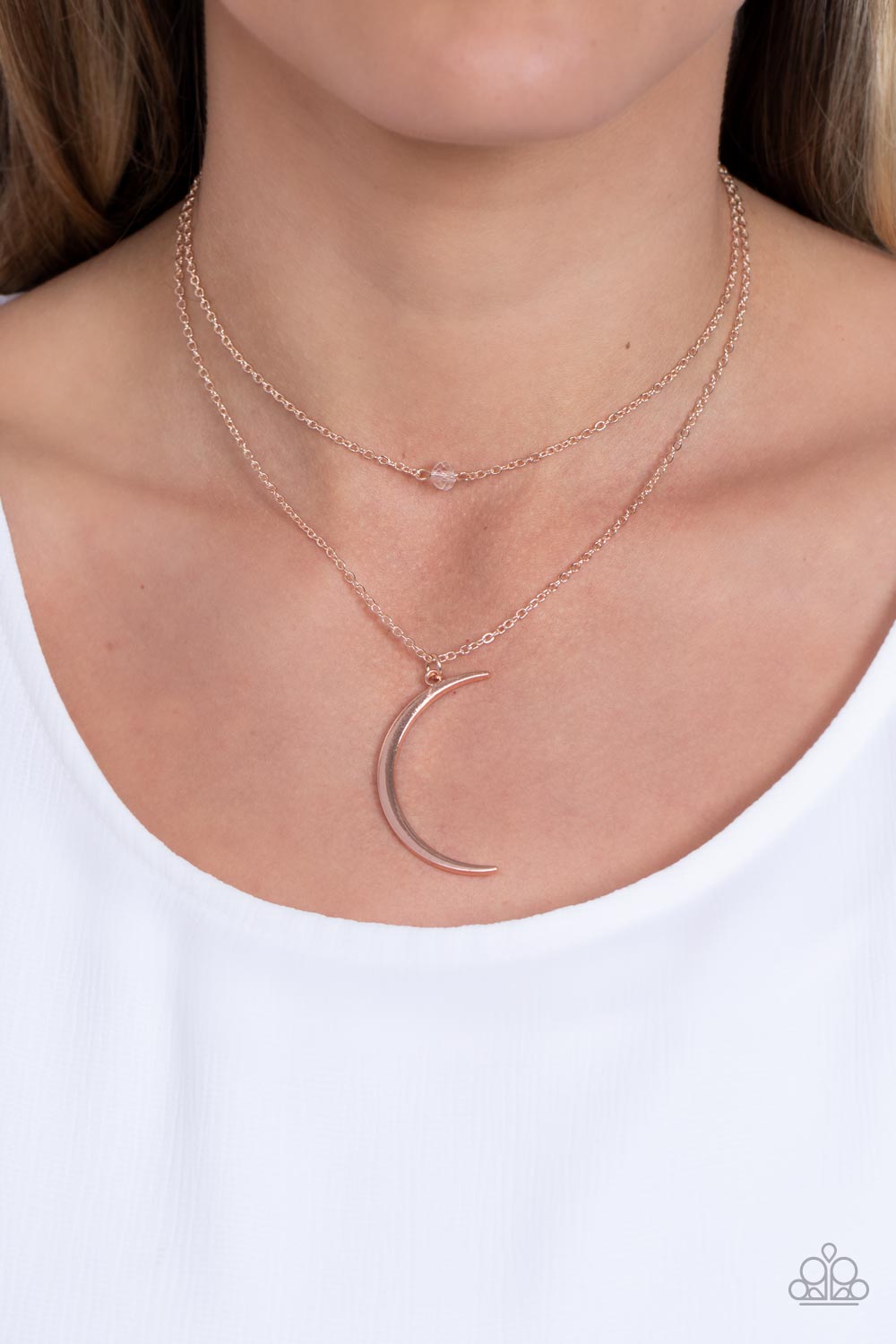 Paparazzi Accessories Modern Moonbeam - Rose Gold Two dainty rose gold chains delicately layer below the collar. A white crystal-like bead sparkles at the center of the uppermost chain while a rose gold half moon pendant swings from the bottom of the disp