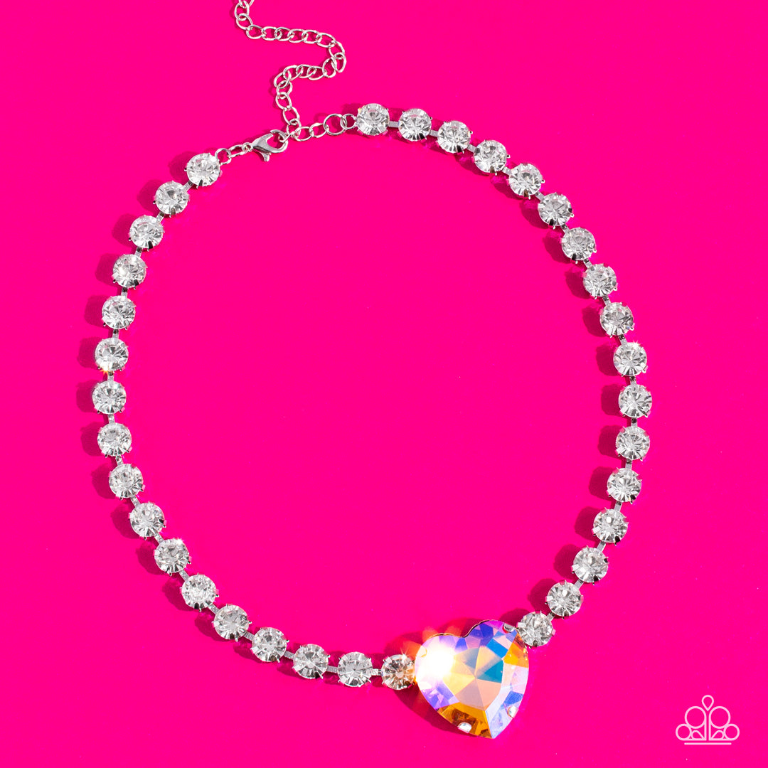 Paparazzi Accessories Heart in My Throat - Orange A dramatically oversized heart-shaped gem with a reflective, iridescent orange finish glitters at the center of a blinding row of glassy white rhinestones, resulting in a flirtatious sparkle around the nec
