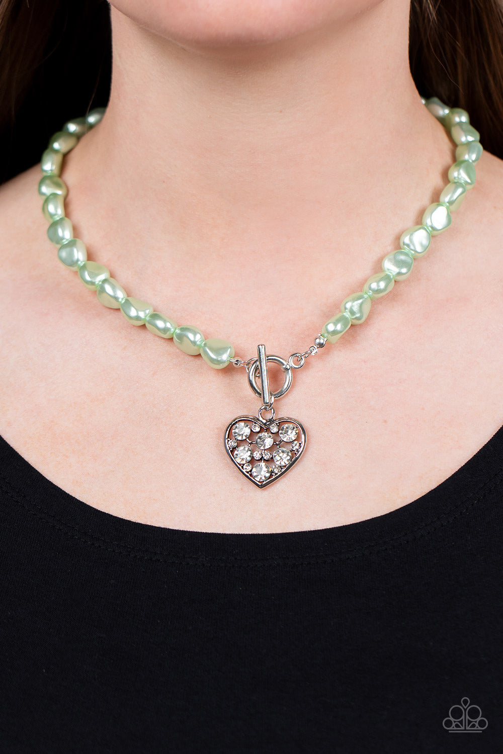 Paparazzi Accessories Color Me Smitten - Green An imperfect collection of pearly green beads are threaded along an invisible wire below the collar, creating a colorful display. Dotted in glittery white rhinestones, an airy silver heart pendant sparkles at