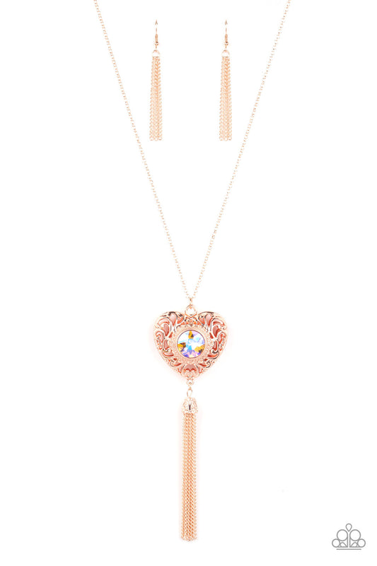 Paparazzi Accessories Prismatic Passion - Gold A magical iridescent peach gem sparkles at the center of a 3-dimensional rose gold heart. Filled with vine-like filigree, the locket inspired heart frame glides along an extended rose gold chain while a shimm