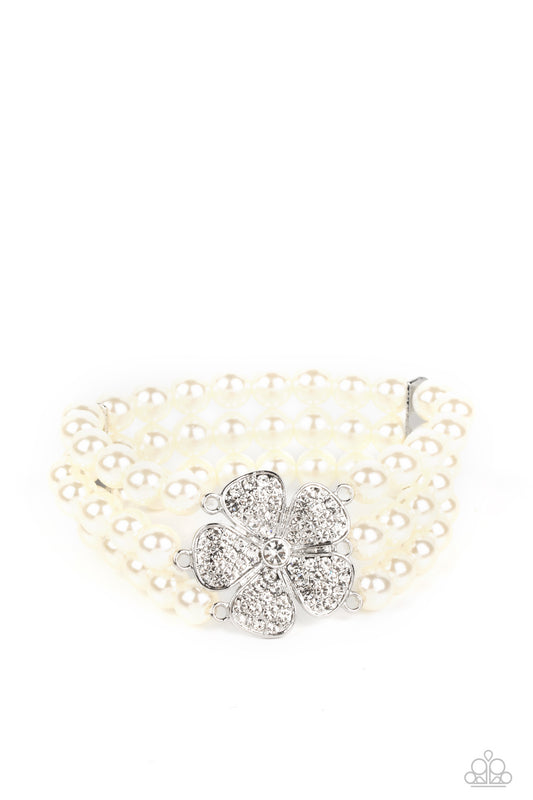 Paparazzi Accessories Park Avenue Orchard - White Separated by dainty silver plates, classic white pearls are threaded along three stretchy bands around the wrist. Encrusted in glassy white rhinestones, a glitzy silver flower blooms at the center of the w
