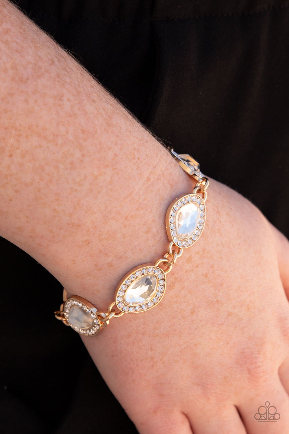 Paparazzi Accessories Next-Level Sparkle - Gold Bordered in gold frames dotted with tiny flecks of white rhinestones, a pair of asymmetrical white gems delicately link into a spellbinding sparkle around the wrist. Features an adjustable clasp closure. Sol