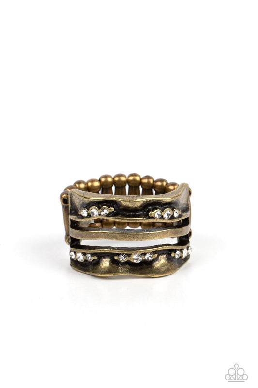Paparazzi Accessories Unexpected Treasure - Brass Dotted with dainty white rhinestones, warped folds of brass create brass bars across the finger, invoking rustic refinement. Features a stretchy band for a flexible fit. Sold as one individual ring. Rings