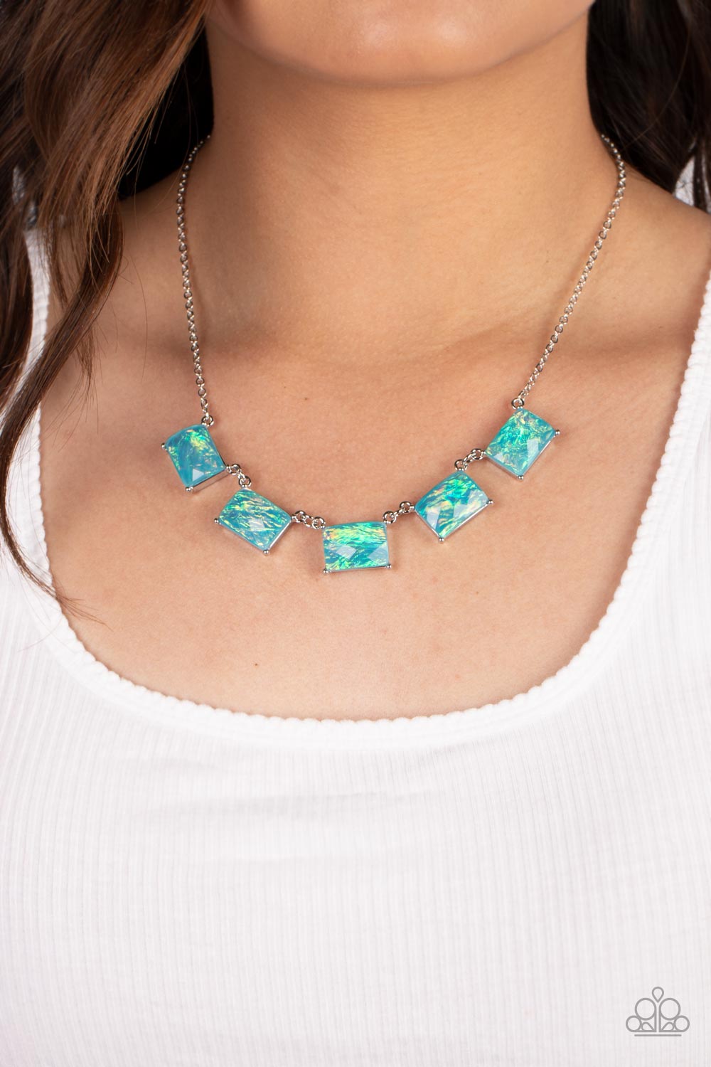 Paparazzi Accessories Opalescent Oblivion - Blue Featuring a refracted shimmer and an opalescent finish, a collection of emerald-cut, glassy blue gems link along the collar to create a hypnotic pop of color. Each gem is pressed into a silver frame with pr