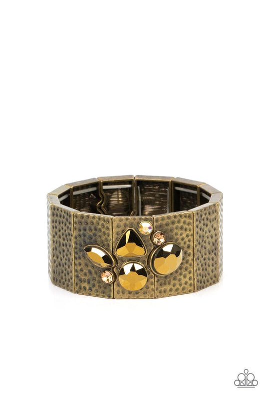 Paparazzi Accessories Flickering Fortune - Brass Hammered in gritty shimmer, rustic, rectangular, brass frames are threaded along stretchy bands that wrap around the wrist. Mismatched topaz, iridescent, and aurum rhinestones cluster on the front and back