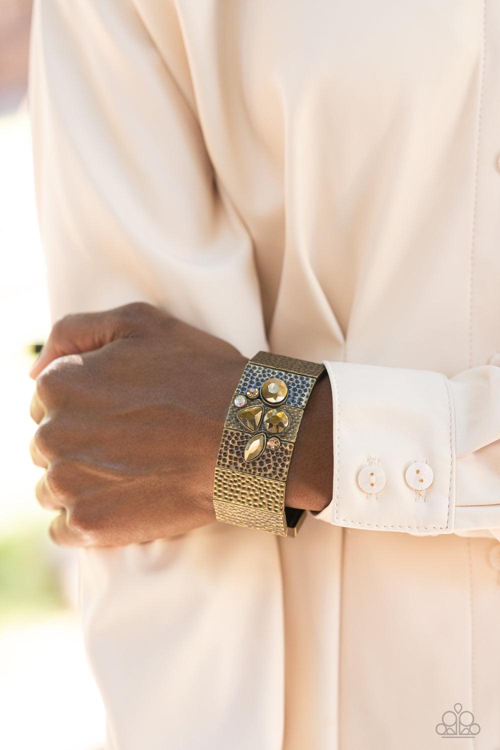 Paparazzi Accessories Flickering Fortune - Brass Hammered in gritty shimmer, rustic, rectangular, brass frames are threaded along stretchy bands that wrap around the wrist. Mismatched topaz, iridescent, and aurum rhinestones cluster on the front and back