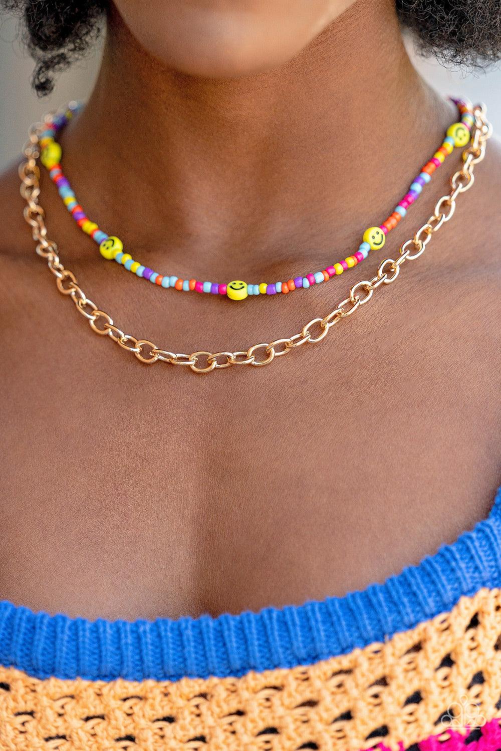 Paparazzi Accessories Happy Looks Good on You - Multi Layered together with a bold gold chain, dainty multicolored seed beads and yellow smiley face beads are threaded along an invisible wire below the collar, resulting in a colorfully retro design. Featu