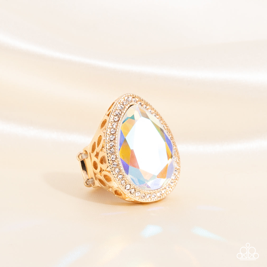 Paparazzi Accessories Illuminated Icon - Gold An oversized teardrop gem with an iridescent finish is nestled inside a gold teardrop frame encrusted in dainty white rhinestones. Airy teardrop cutouts decorate each side of the oversized frame, some with sub