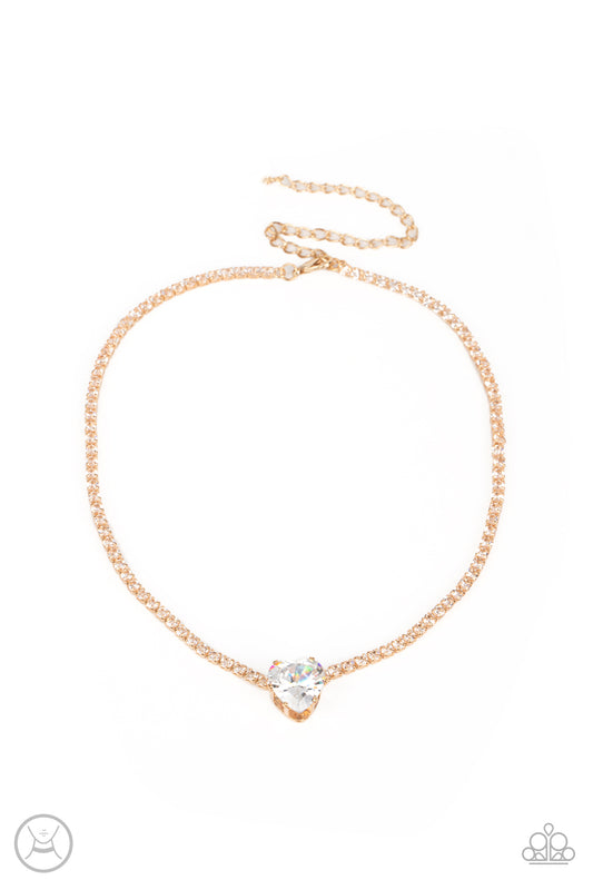 Paparazzi Accessories Flirty Fiancé - Gold An oversized white heart-shaped gem, set in an airy, pronged gold fitting, glitters at the center of a blinding row of dainty, glassy white rhinestones set in square gold fittings, resulting in a flirtatious spar