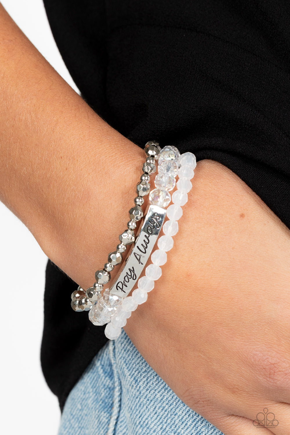 Paparazzi Accessories Pray Always - White Varying in shape and shimmer, faceted silver beads, milky white beads, and glittery crystal-like beads are threaded along elastic stretchy bands, creating colorful layers across the wrist. Featured on the crystal-