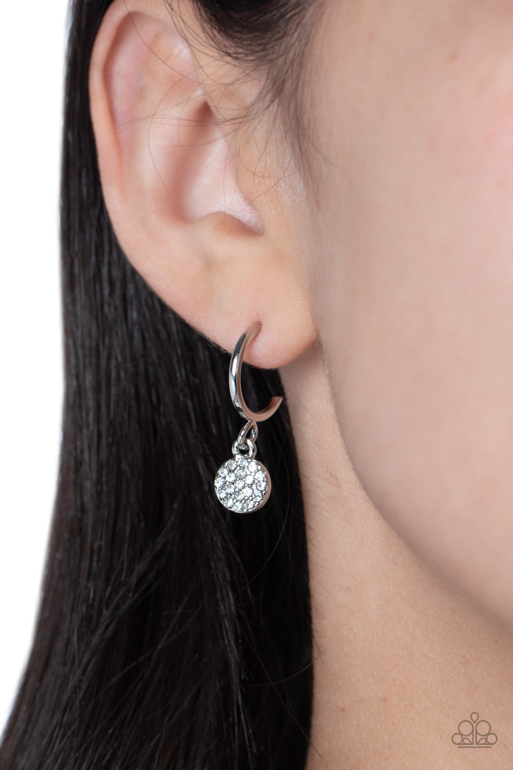Paparazzi Accessories Bodacious Ballroom - White Swinging from a glistening silver hoop, a dainty silver disc, embossed with white rhinestones glimmers, adding a subtle shimmer around the ear. Earring attaches to a standard post fitting. Hoop measures app