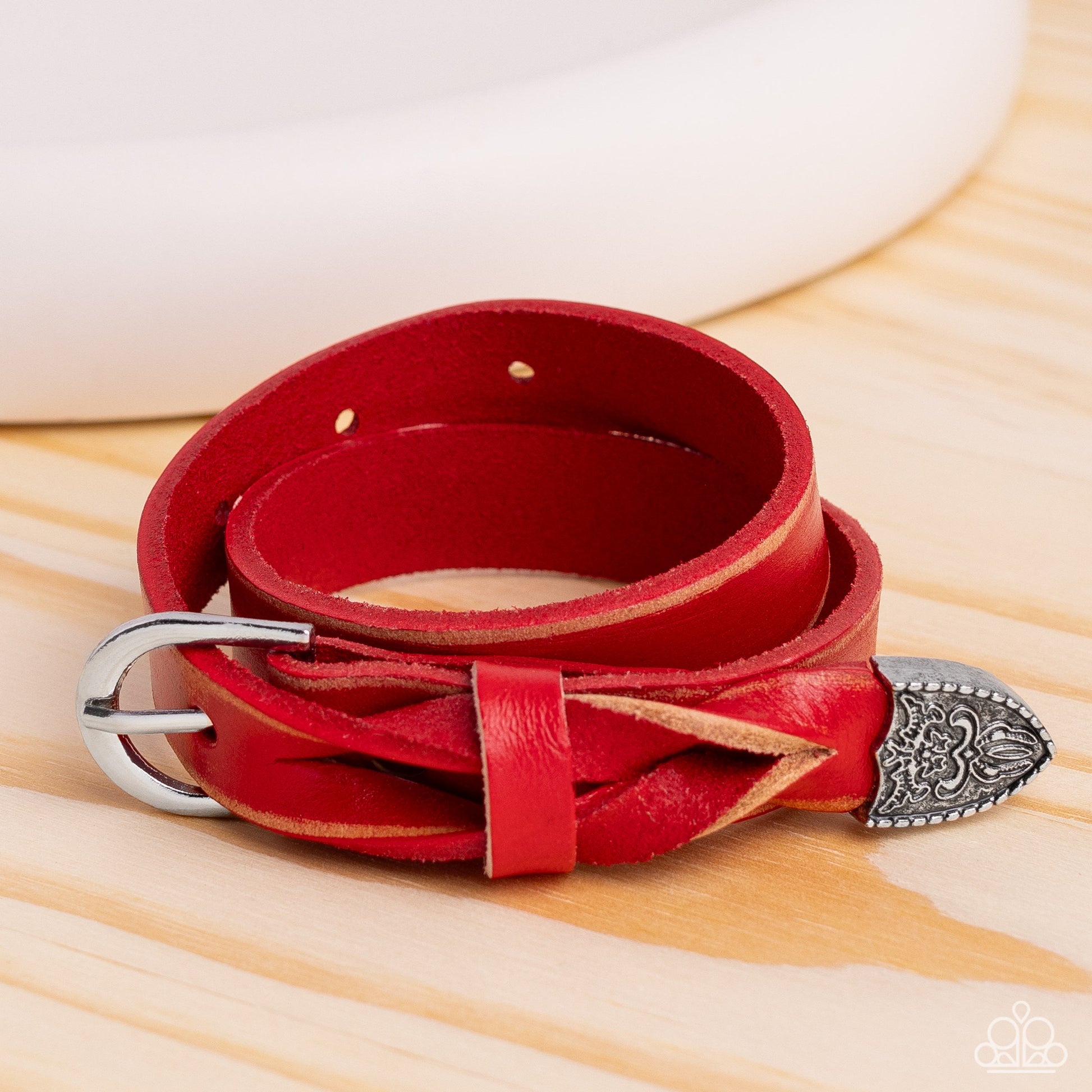 Paparazzi Accessories Coat of Arms Couture - Red Featuring a weathered finish, a red leather band loops around the wrist in a belt loop fashion. Featured at the end of the loop, the leather braids into a silver cap fitting, embossed with a coat of arms st