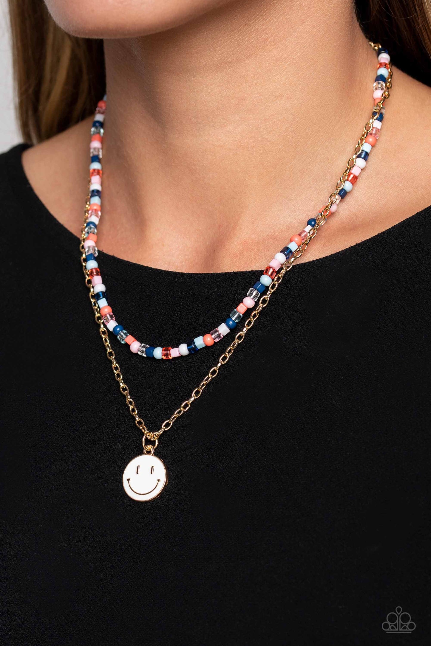 Paparazzi Accessories High School Reunion - Blue Gliding from a dainty, gold chain, a smiley face pendant stands out against a white backdrop. Completing the charismatic ensemble, a collection of seed beads in shades of Spun Sugar, baby pink, navy blue, w