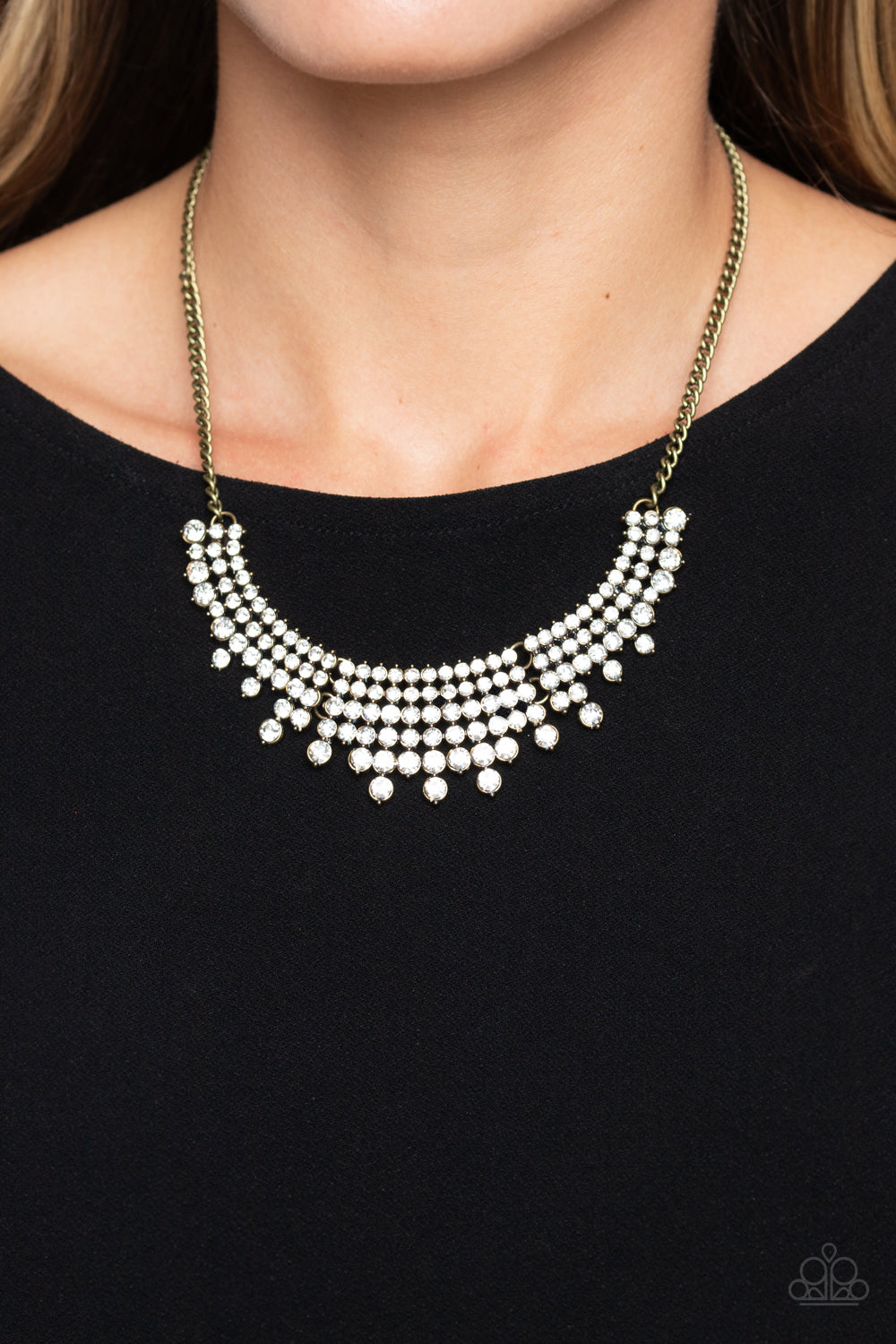 Paparazzi Accessories Shimmering Song - Brass Shimmery strands of white rhinestones in varying sizes majestically morph into brass-framed layers along the collar for a sparkling statement piece. Features an adjustable clasp closure. Sold as one individual