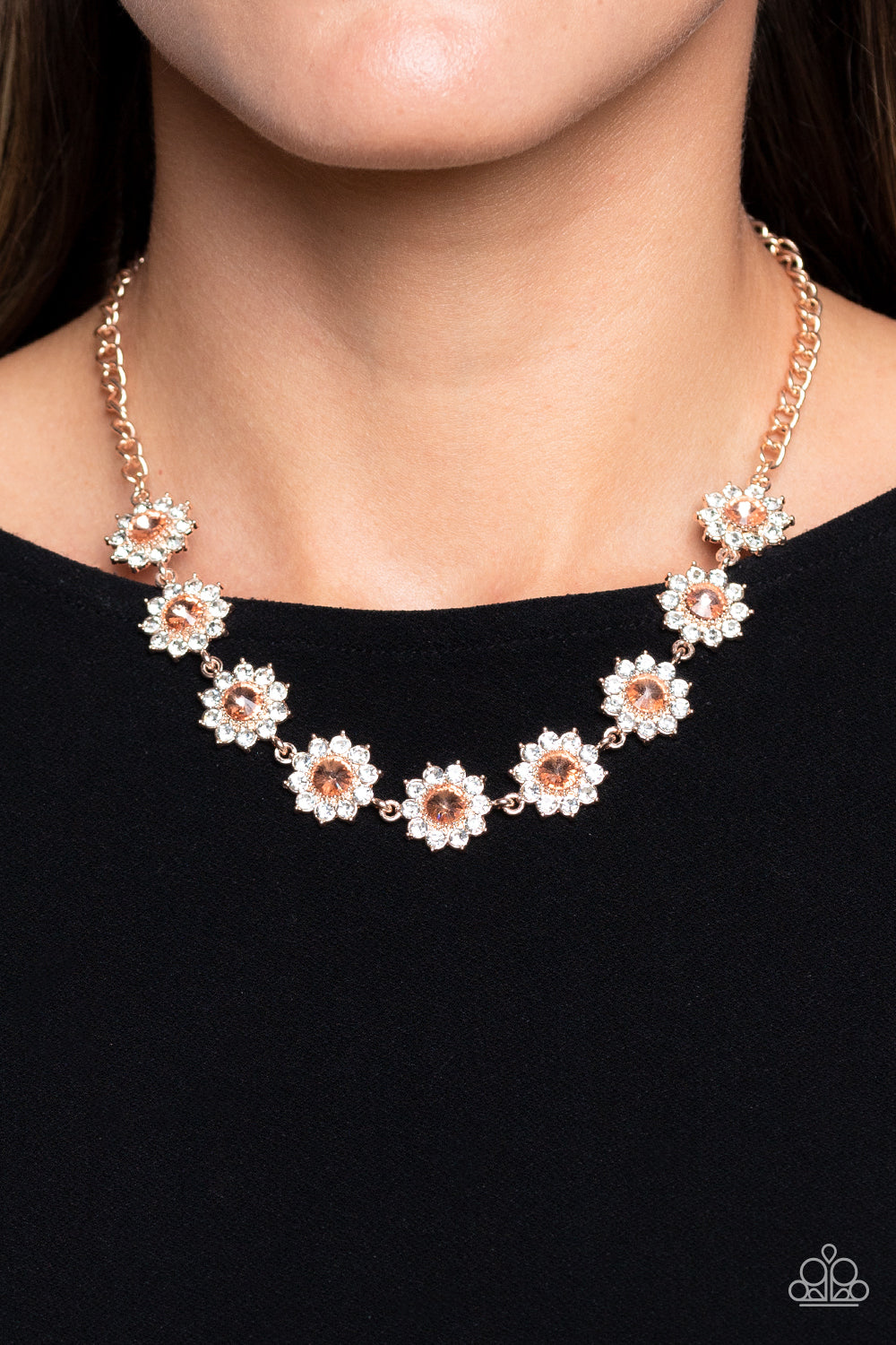 Paparazzi Accessories Blooming Brilliance - Rose Gold Shiny white rhinestone petals bloom from a shimmery peachy center, creating a whimsical floral arrangement of rose gold below the collar. Features an adjustable clasp closure. Sold as one individual ne