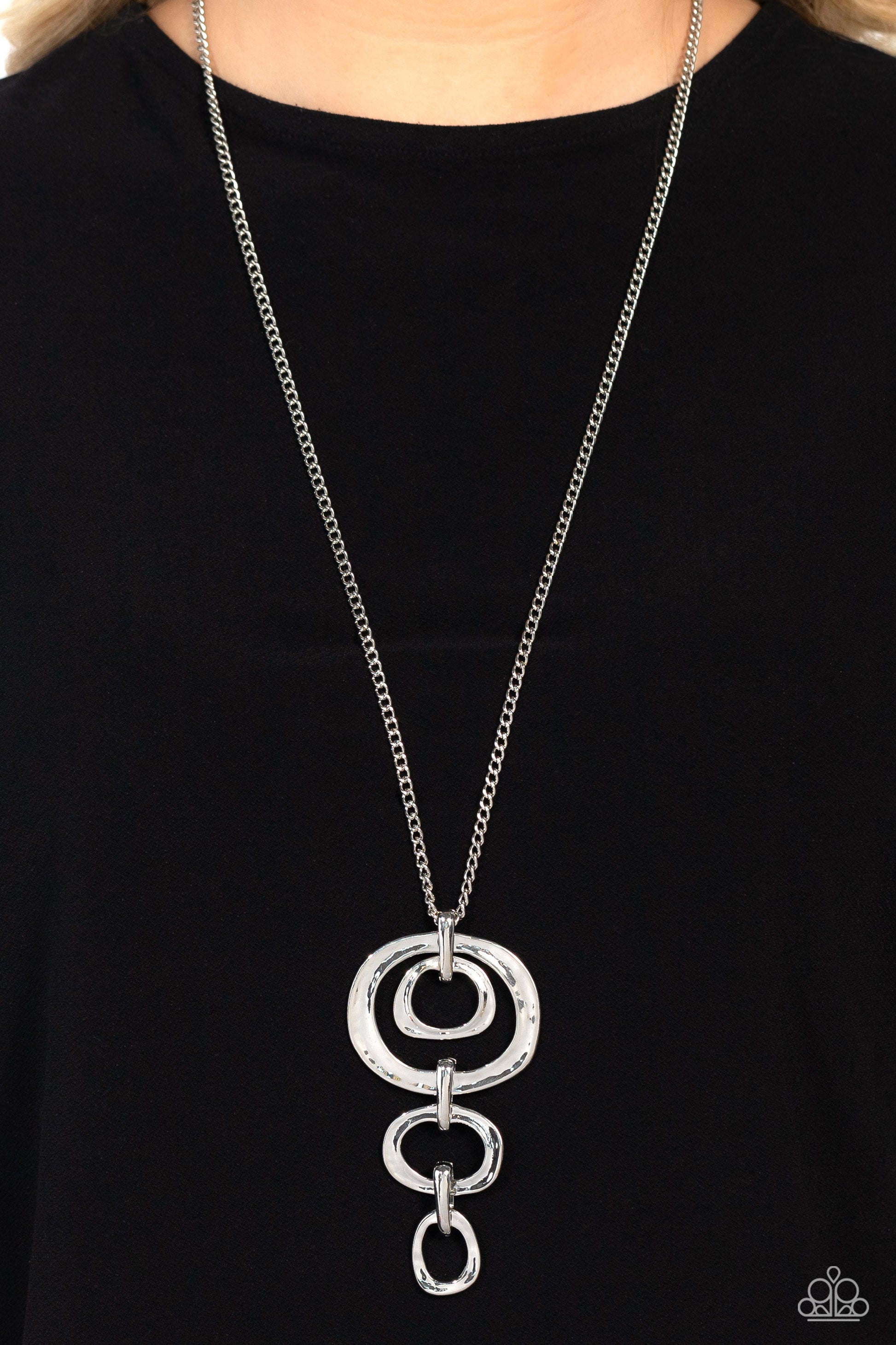Paparazzi Accessories Tranquil Trickle - Silver Trickling down the chest from an elongated silver chain, a mismatched assortment of hammered silver abstract rings glistens in this monochromatic masterpiece. Features an adjustable clasp closure. Sold as on