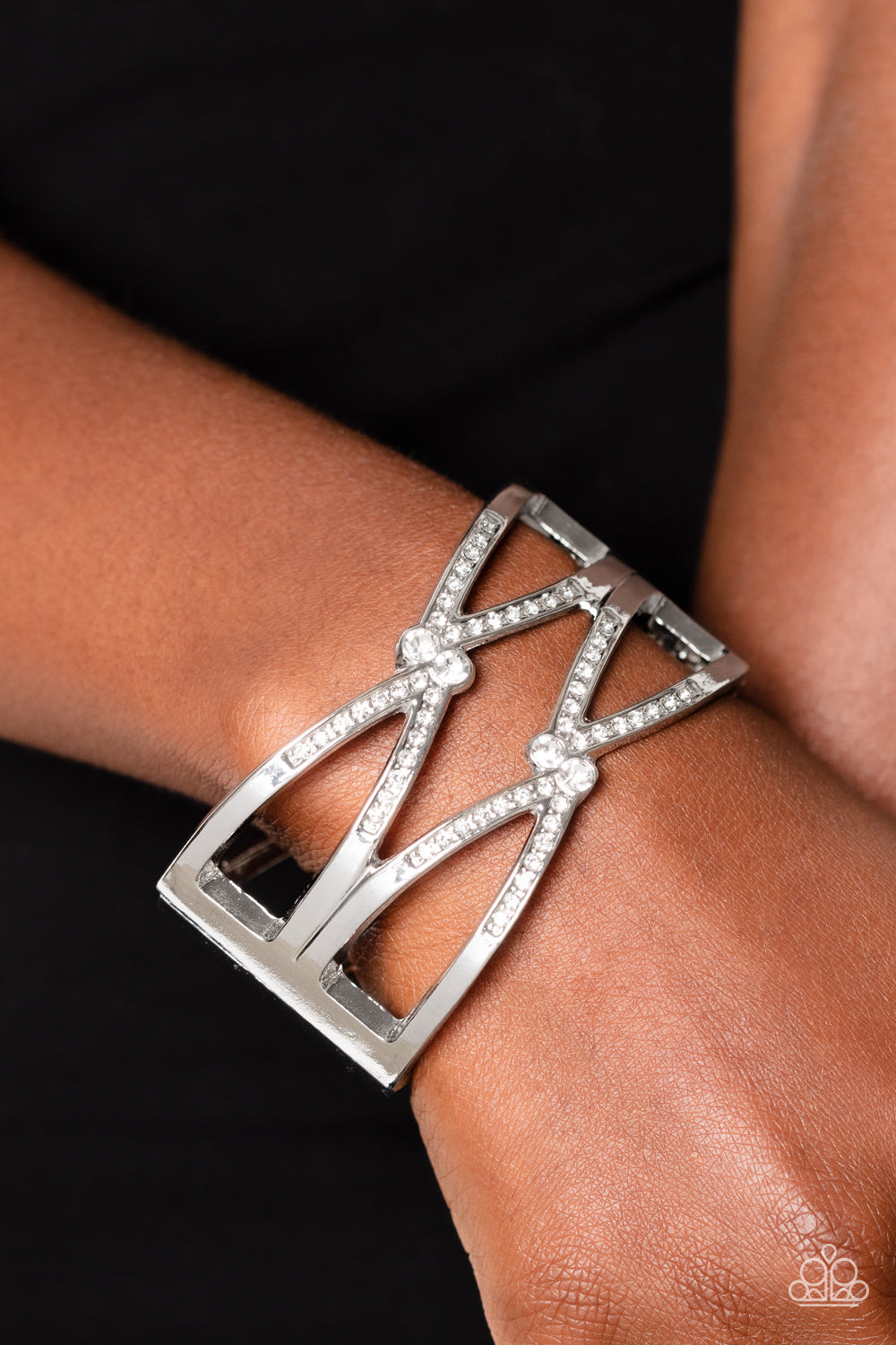 Paparazzi Accessories Entrancing Etiquette - White High-sheen silver bars airily weaves around the wrist in a zig-zag manner into a refined statement. Featured on the crossed ribbons of the silver, rows of dainty white rhinestones cluster across the displ