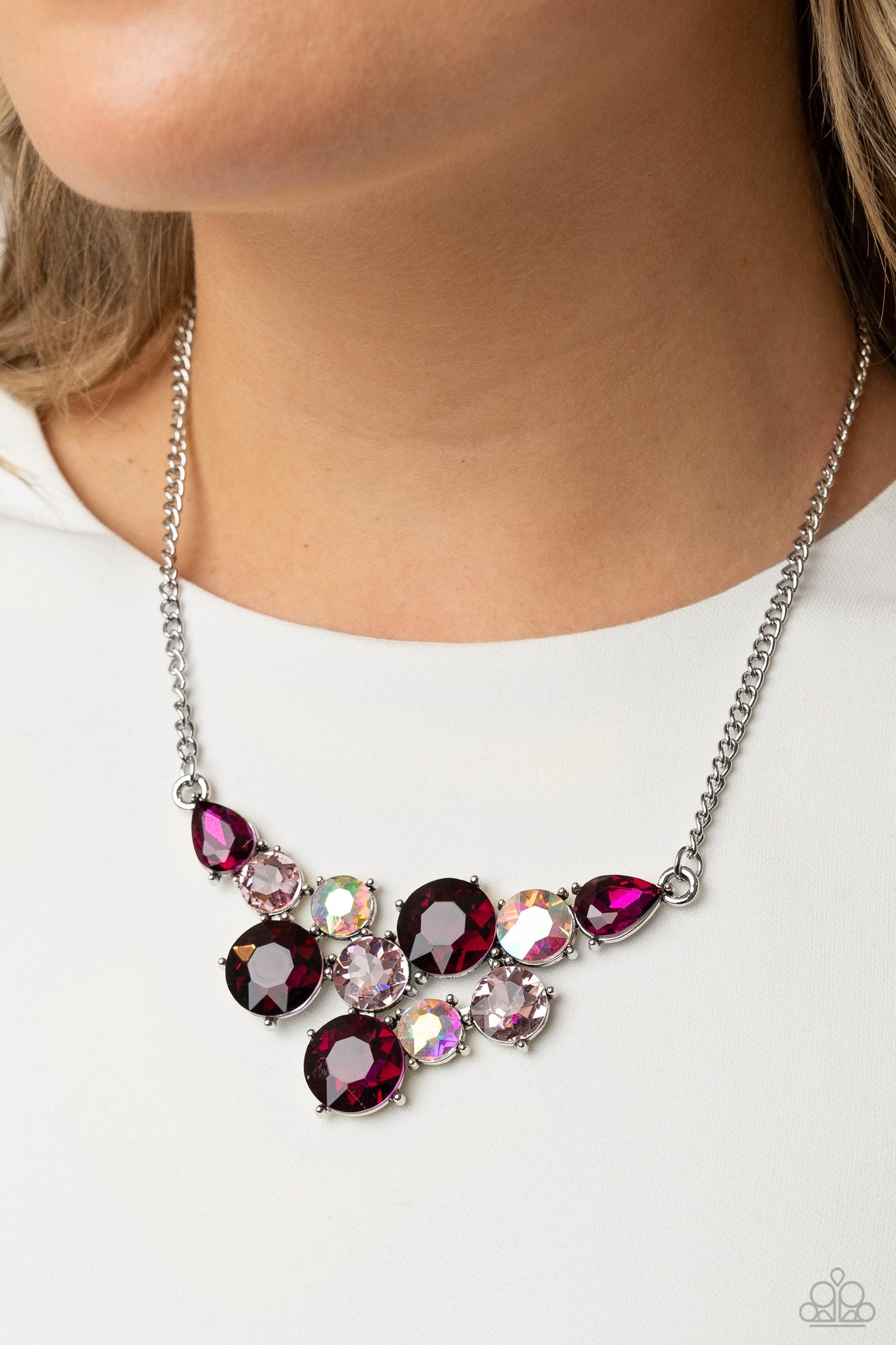 Paparazzi Accessories Round Royalty - Pink An explosion of round gems in varying sizes bordered by teardrop gems cluster together to create a glittery pink fringe down the neckline. Featured in fuchsia, light pink, and iridescent hues, each gem reflects l