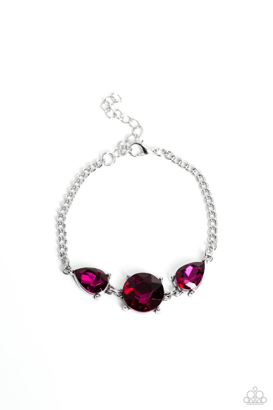 Paparazzi Accessories Twinkling Trio - Pink An oversized round gem bordered by teardrop gems cluster together to create a glittery silver collection around the wrist. Featured in a fuchsia hue, each gem reflects light off of its faceted surface emitting f