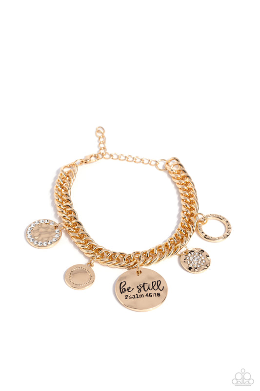 Paparazzi Accessories GLITTER and Grace - Gold Gliding from a thick gold curb chain, a collection of refined charms adds some texture and shimmer to this monochromatic mash-up. An oversized, hammered disc is stamped with the phrase "be still" with the scr