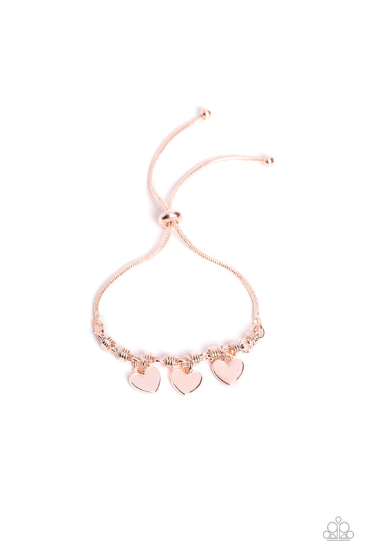 Paparazzi Accessories Romance Tale - Rose Gold Dangling from a rose gold snake chain, a trio of rose gold hearts link across the wrist for a dash of swoon-worthy sheen. Infused along the heart chain, rose gold spiral-like accents add additional texture to